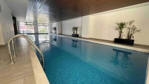 An indoor swimming pool with a wooden ceiling, tiled floor, and potted plants along the walls. - Loft Estudio Cdmx Alberca y Gym / Smart Penthouse (Ciudad de México)