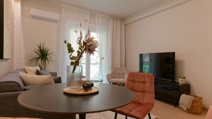 Un salon moderne avec une table ronde, un canapé, un téléviseur et une plante en pot.