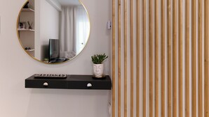 Une salle de bain moderne avec un miroir rond, un meuble-lavabo noir, une plante en pot et un panneau en bois à rayures.