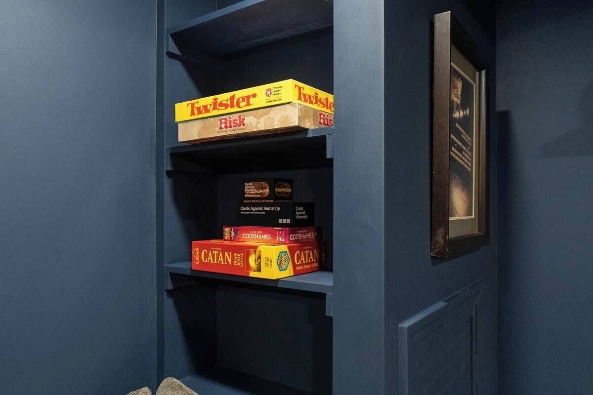 A bookshelf with board games including Twister Risk and Catan.