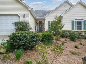 A residential house with a garage, a front door, and a small garden area with various plants and shrubs. - Sleeps 14, Game Room,Movie Theater,Dock +MORE (Eatonton)