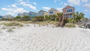 Eine Strandimmobilie mit mehreren Häusern, Sandstrand und Holzstegen.