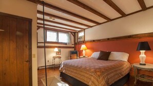 A bedroom with a large bed, two bedside lamps, a wooden door, and a window with curtains. - Race Brook Lodge  (Sheffield)