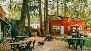 An outdoor patio area with tables and chairs, a fire pit, and a red building in the background. - Race Brook Lodge  (Sheffield)