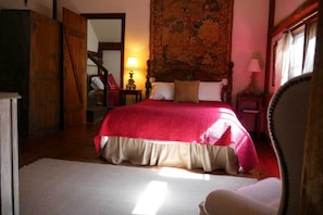 A bedroom with a large bed, a wooden wardrobe, a mirror, a lamp, and a tapestry on the wall. - Race Brook Lodge  (Sheffield)