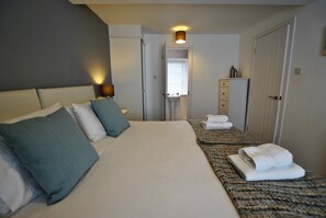 Cozy retreat with a large bed, bedside table, and wardrobe, featuring a bathroom through the doorway.