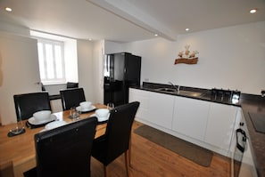 Enjoy meal preparation in this well-equipped kitchen with a sleek refrigerator, stainless steel sink, and ample cabinetry.