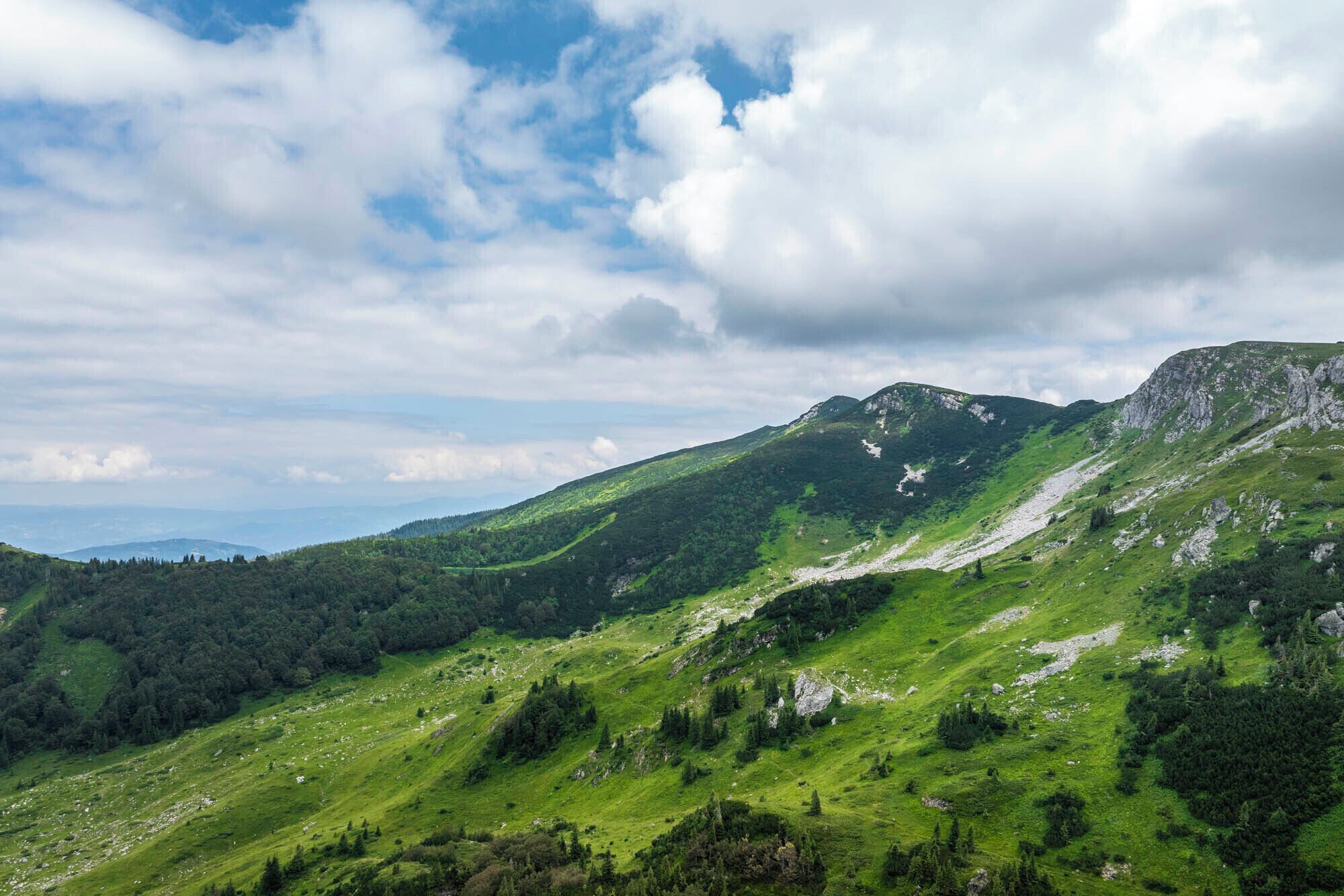 Een bergachtig landschap met groene valleien en rotsachtige rotsformaties.