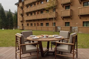 A round wooden table with six chairs, set outdoors with a building in the background. - Swissôtel Resort Kolasin (Vranjak)