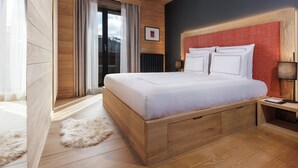 A wooden bed with a red headboard, a bedside table with a lamp, and a view of the outdoors through a sliding door.