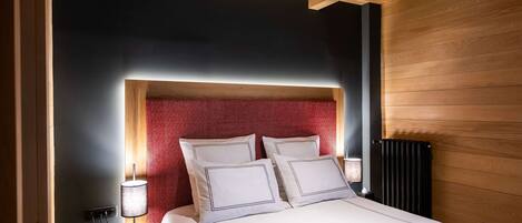 A modern bedroom with a wooden ceiling, a red patterned headboard, and a bedside table with a lamp and phone.