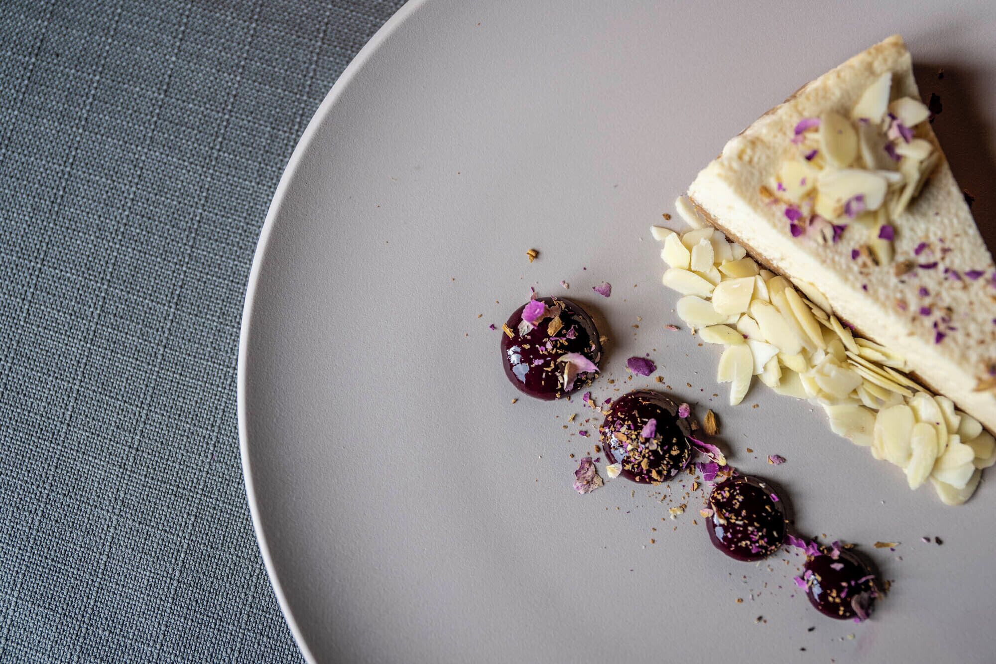 Un plato con un postre que incluye algo cubierto de chocolate, almendras en rodajas y un trozo de pan.