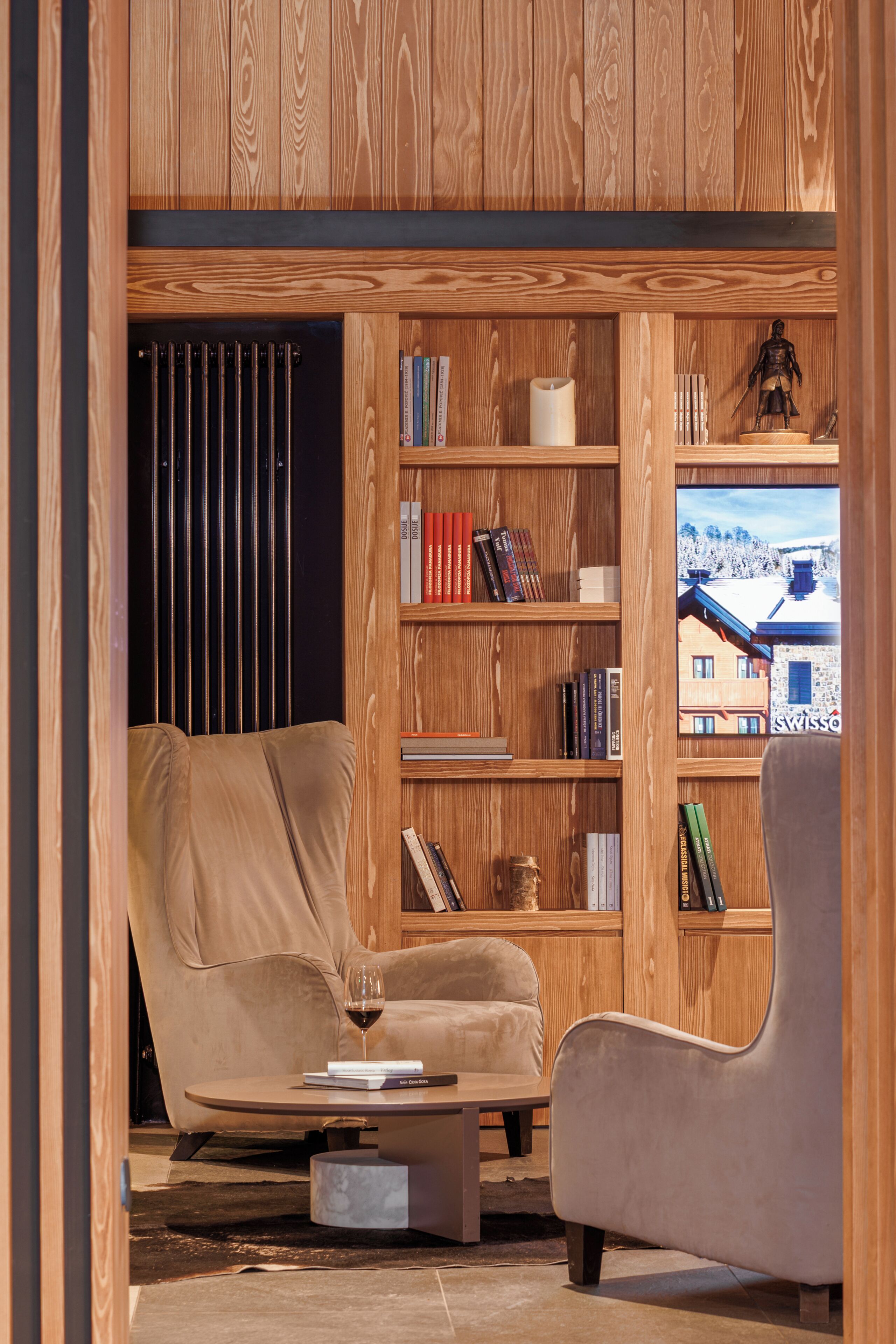 A cozy living room with a wooden bookshelf, a comfortable armchair, a sofa, and a coffee table.