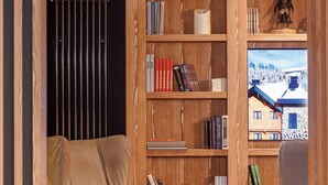 A cozy living room with a wooden bookshelf, a comfortable armchair, a sofa, and a coffee table.