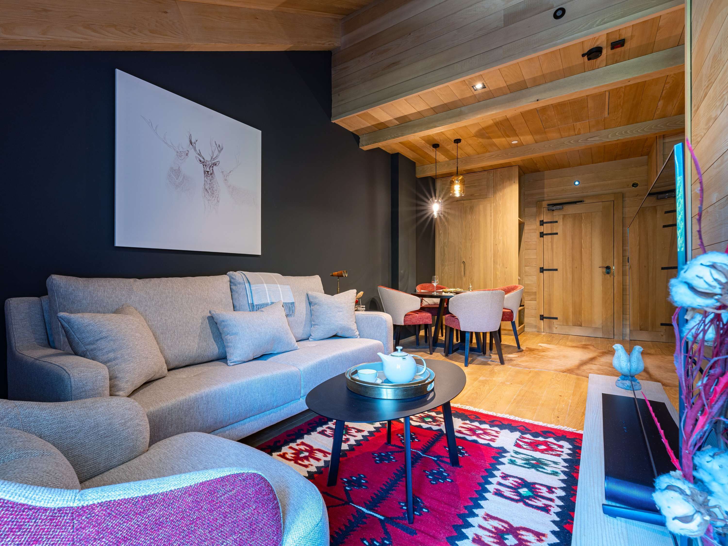 A modern living room with a grey sofa, a round coffee table, and a vibrant rug.