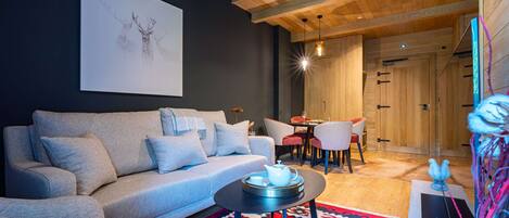 A modern living room with a grey sofa, a round coffee table, and a vibrant rug.