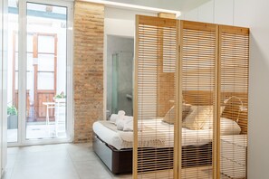 A modern bedroom with a large bed, a sliding glass door leading to an outdoor area, and a brick wall. - APARTUP LAS ARENAS BEACH MALVARROSA WIFI AIRE ACONDICIONADO (Valencia / València)
