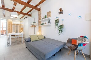 A modern living room with a grey sofa, a dining table with chairs, and a small seating area with a colorful chair. - APARTUP LAS ARENAS BEACH MALVARROSA WIFI AIRE ACONDICIONADO (Valencia / València)