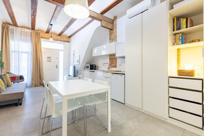 A modern kitchen with white cabinets, a dining table, and a built-in bookshelf.