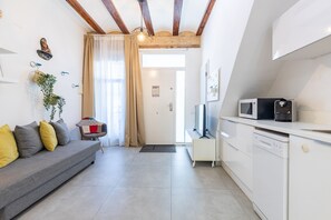 A modern living room with a grey sofa, a small dining area with a microwave, and a kitchen with white cabinets. - APARTUP LAS ARENAS BEACH MALVARROSA WIFI AIRE ACONDICIONADO (Valencia / València)