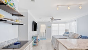 A modern kitchen with a flat-screen TV, a ceiling fan, and a dining area with a marble countertop. - Sand and Ocean Lovers Beaach Home! (Panama City Beach)