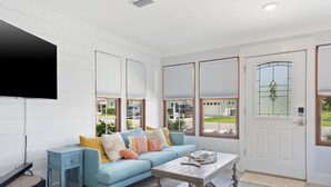 A modern living room with a light blue sofa, a coffee table, and a flat-screen TV mounted on the wall. - Sand and Ocean Lovers Beaach Home! (Panama City Beach)