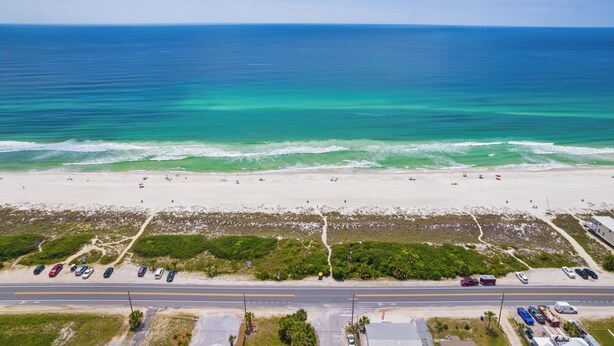An aerial view of a beach with a road in the foreground and a clear blue ocean in the background. - Sand and Ocean Lovers Beaach Home! (Panama City Beach)