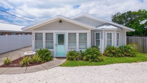 A single-story house with a front porch, a garage, and a small garden with palm plants. - Sand and Ocean Lovers Beaach Home! (Panama City Beach)