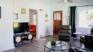 Un salon moderne doté d’un téléviseur à écran plat, de fauteuils en cuir, d’une table basse en verre et d’un ventilateur de plafond.