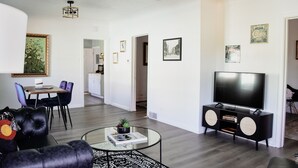 Un salon moderne avec une table basse en verre, un canapé en cuir noir et un téléviseur à écran plat posé sur un meuble noir.