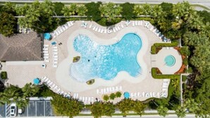 Vista aérea de un resort con una piscina grande, zonas de descanso y vegetación circundante.
