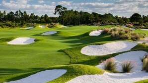 Campo de golf con bunkers de arena y un fondo arbolado.