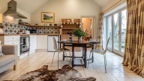 Una cocina moderna con comedor, que cuenta con un amplio ventanal, una mesa de madera y un sofá.