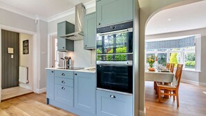 Une cuisine moderne avec des meubles de couleur bleu clair, un four encastré et un coin repas avec une table dressée pour quatre personnes.