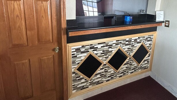 A wooden door, a reception desk with a clock, and a tiled floor. - Royal Rest Motel  (Chariton)