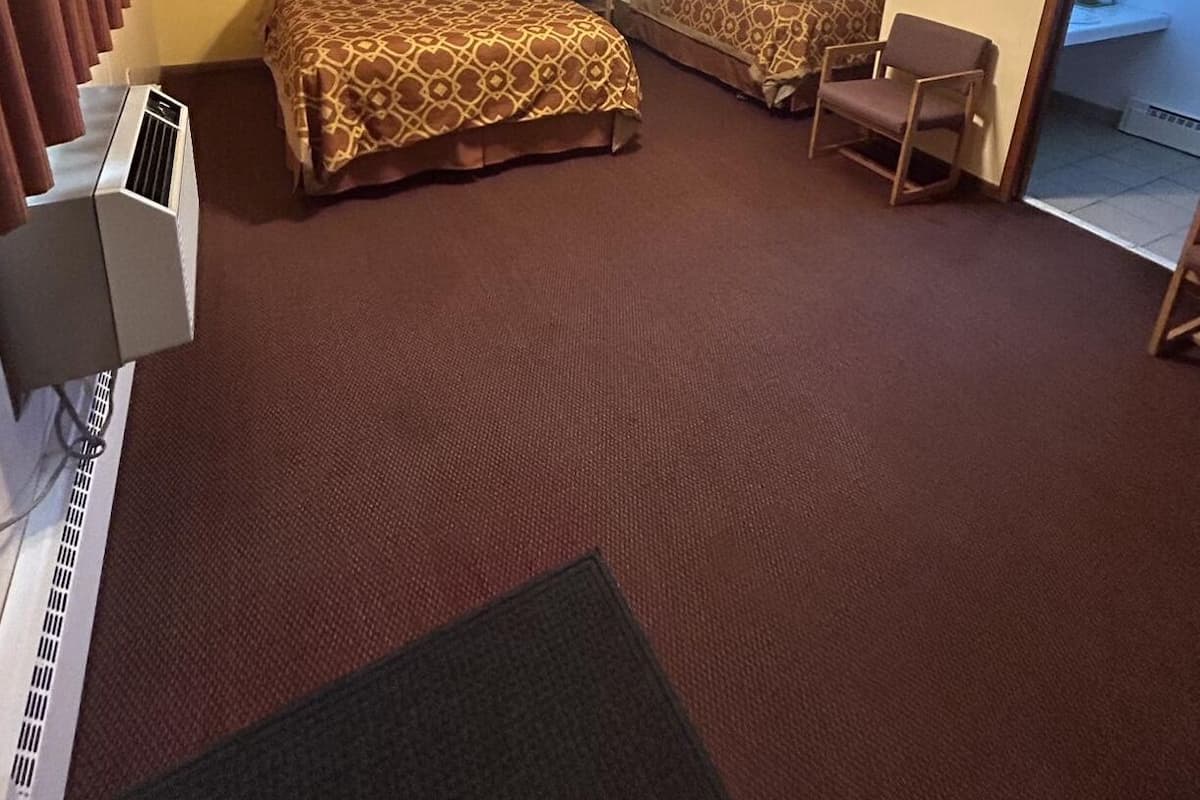 A hotel room with two beds, a ceiling fan, a desk, and a chair.