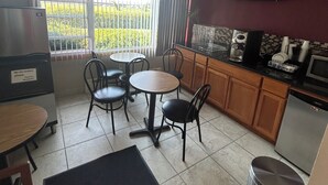 A compact kitchen with a dining area, a ceiling fan, and a view through the window. - Royal Rest Motel  (Chariton)
