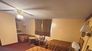 A hotel room with a bed, a desk, a chair, a ceiling fan, and a window with curtains. - Royal Rest Motel  (Chariton)
