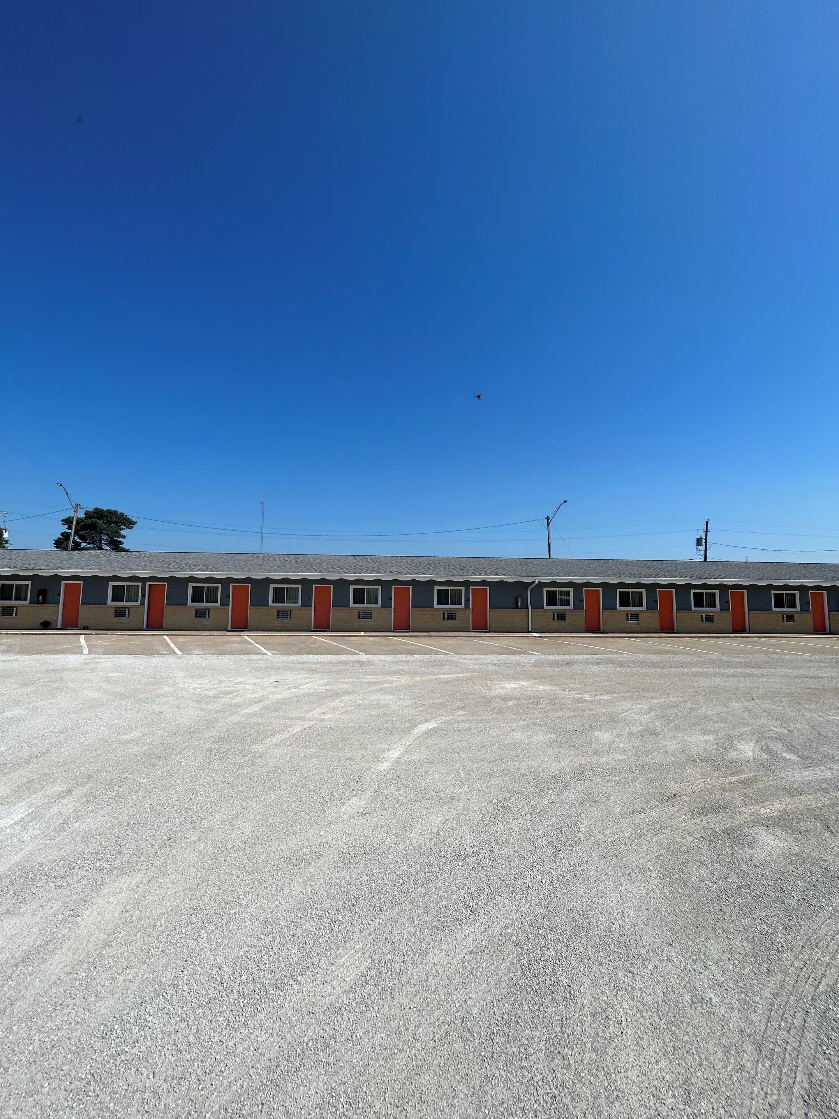 A large parking lot with a row of motel-style buildings in the background.