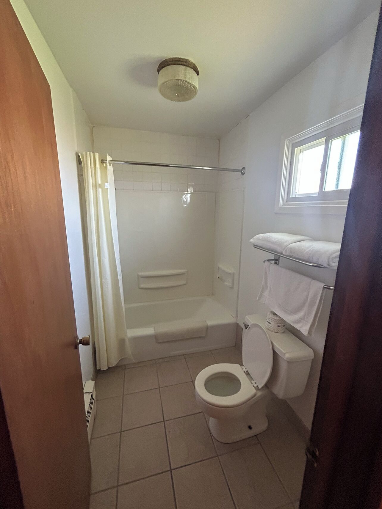 Et badeværelse med toilet, bruser og badekar.