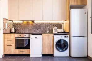 A modern kitchen with wooden cabinets, a built-in oven, a dishwasher, a washing machine, and a refrigerator.