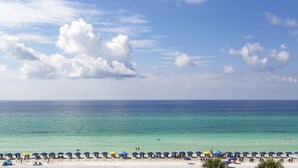 A beach with clear turquoise water, a row of umbrellas, and a sandy shore. - Stunning Beach, Golf Course and Bay Views!  Empress 1103 (Miramar Beach)
