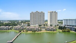 A high-rise hotel with multiple floors, a central courtyard, and a body of water in front. - Stunning Beach, Golf Course and Bay Views!  Empress 1103 (Miramar Beach)