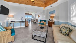A spacious living area with a high ceiling, wooden beams, and a dining area with wicker furniture. - Stunning Beach, Golf Course and Bay Views!  Empress 1103 (Miramar Beach)