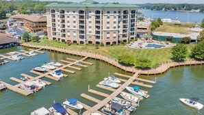 Un hotel de varios pisos con un patio central, barcos amarrados y vista a un lago.