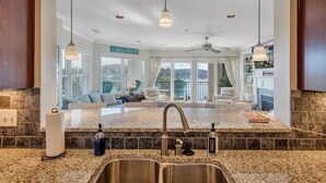 Una cocina con encimeras de granito, pileta de acero inoxidable y luces colgantes.