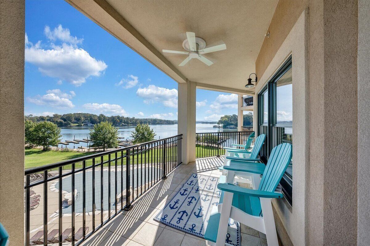 Un balcon avec vue sur un lac, un ventilateur de plafond et des sièges d’extérieur.