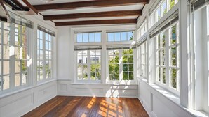 Una habitación con amplios ventanales, vigas de madera y suelo de madera.