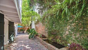 Un camino de ladrillo que conduce a una zona cubierta con un muro de ladrillo cubierto de vegetación.