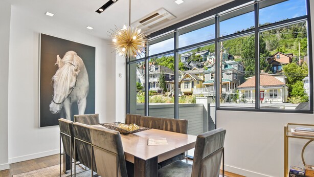 A dining area with a large window, a painting of a horse, and a chandelier. - Parkite on Main (Park City)